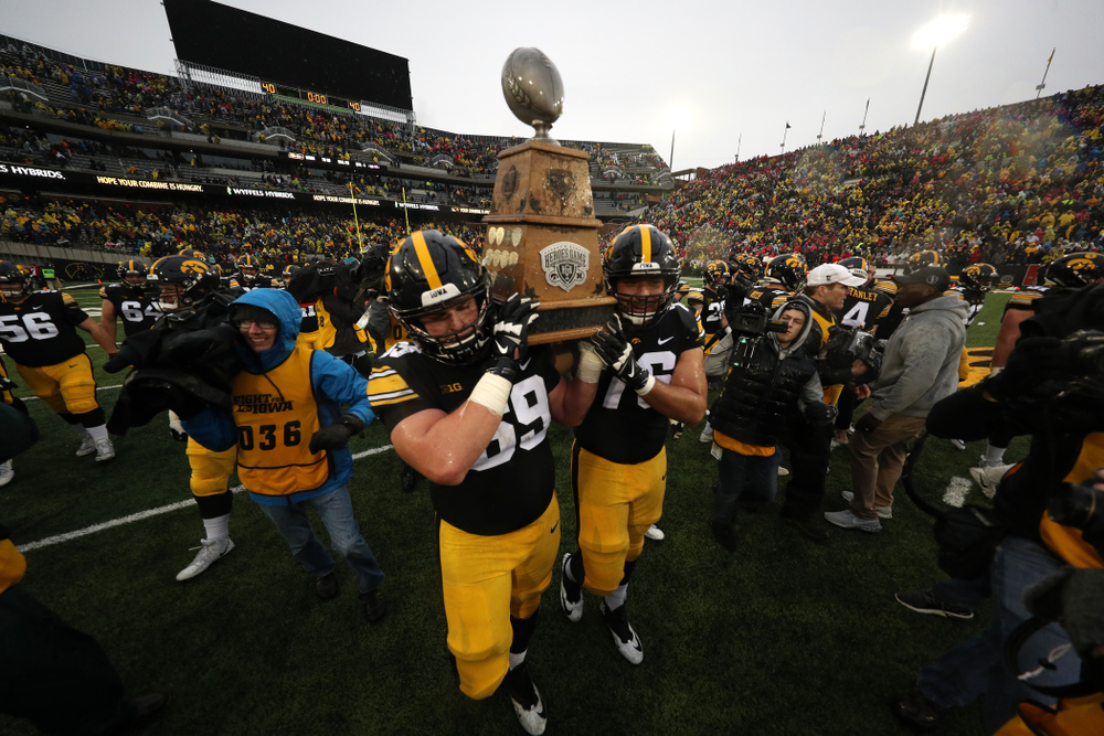 Iowa Hawkeyes offensive lineman Keegan Render (69) and offensive lineman Dalton Ferguson (76) carry the Heroes game trophy off the field following their win over the Nebraska Cornhuskers Friday, November 23, 2018 at Kinnick Stadium. (Brian Ray/hawkeyesports.com)