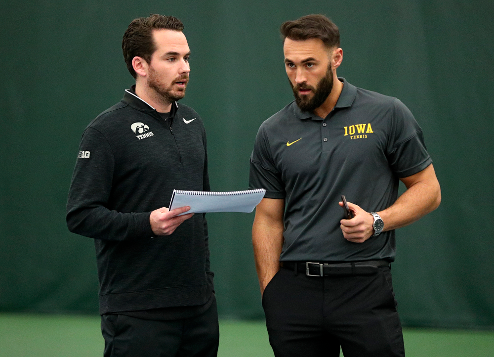 Mellecker Family Head Men's Tennis Coach Ross Wilson (from left) and assistant coach Lloyd Bruce-Burgess talk during a match at the Hawkeye Tennis and Recreation Complex in Iowa City on Friday, February 14, 2020. (Stephen Mally/hawkeyesports.com)