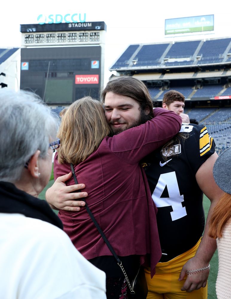 Iowa Hawkeyes offensive lineman Kyler Schott (64) hugs family members following the team photo Wednesday, December 25, 2019 at SDCCU Stadium in San Diego. (Brian Ray/hawkeyesports.com)