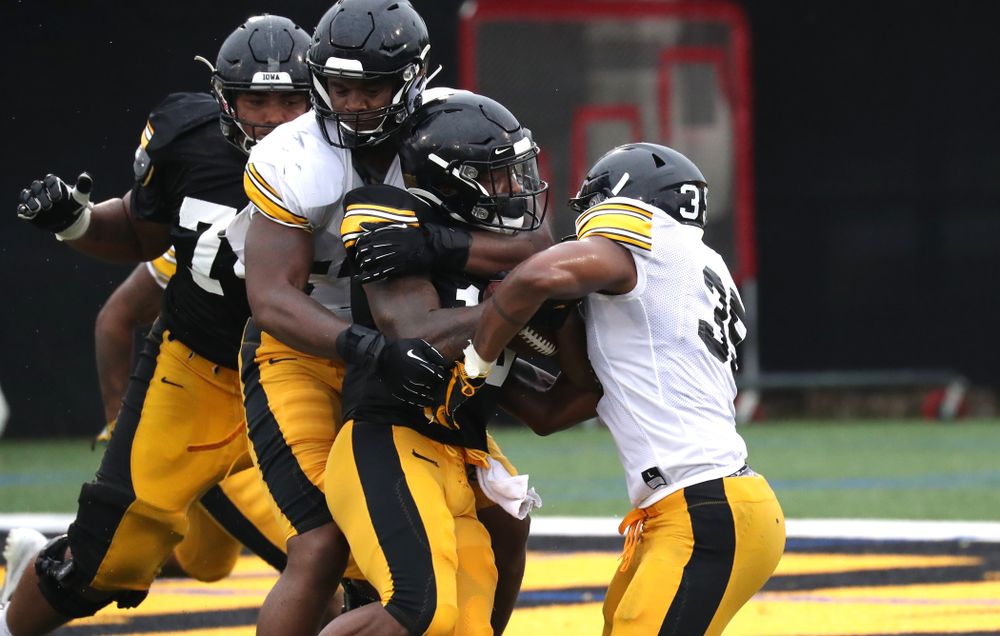 Iowa Hawkeyes defensive end Chauncey Golston (57) and Linebacker Barrington Wade (35) tackle running back Mekhi Sargent (10)