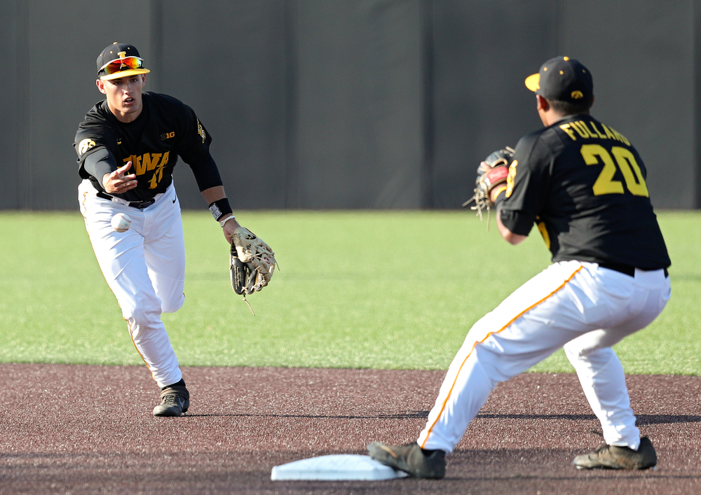 Iowa shortstop Dylan Nedved (from left) tosses the ball to infielder Izaya Fullard (20) as they turn a double play during the second inning of their college baseball game at Duane Banks Field in Iowa City on Tuesday, March 10, 2020. (Stephen Mally/hawkeyesports.com)