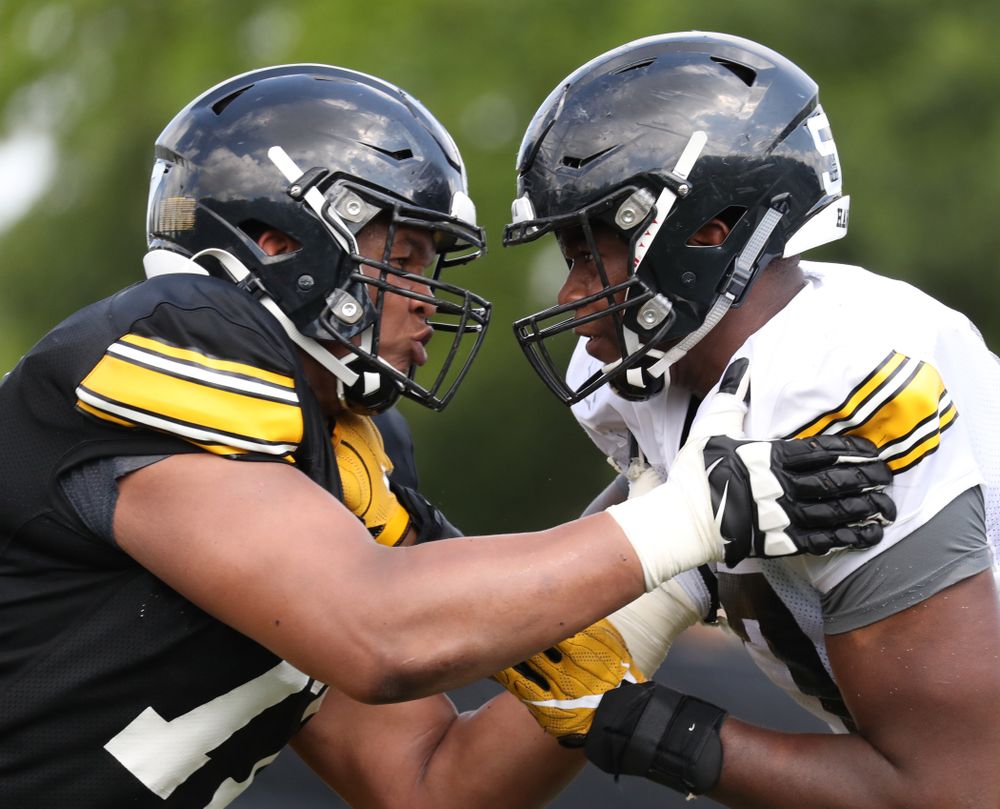 Iowa Hawkeyes offensive lineman Alaric Jackson (77) and Iowa Hawkeyes defensive end Chauncey Golston (57)