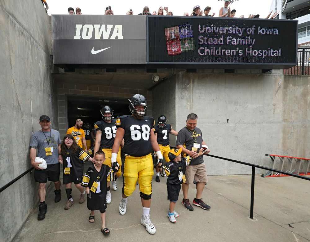 Kid Captains Skylar Hardee (left) and Jeg Weets (right) walk with Iowa Hawkeyes offensive lineman Landan Paulsen (68) prepare to swarm as they exit the tunnel during Kids Day at Kinnick Stadium in Iowa City on Saturday, Aug 10, 2019. (Stephen Mally/hawkeyesports.com)