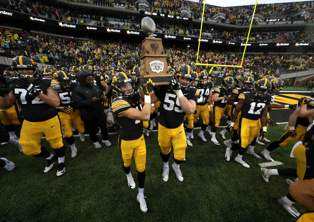 Iowa Hawkeyes wide receiver Kyle Groeneweg (14) and Iowa Hawkeyes offensive lineman Ross Reynolds (59) carry the Heros game trophy off the field following their win over the Nebraska Cornhuskers Friday, November 23, 2018 at Kinnick Stadium. (Brian Ray/hawkeyesports.com)