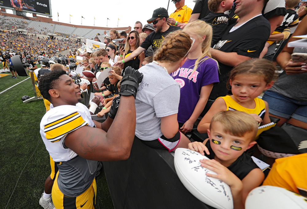 Iowa Hawkeyes defensive end Chauncey Golston (57) signs an autograph on a shirt during Kids Day at Kinnick Stadium in Iowa City on Saturday, Aug 10, 2019. (Stephen Mally/hawkeyesports.com)