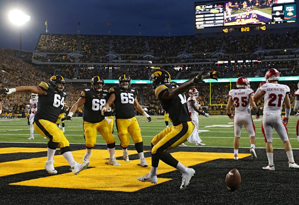 Iowa Hawkeyes offensive lineman Kyler Schott (64), offensive lineman Landan Paulsen (68), and offensive lineman Tyler Linderbaum (65) celebrate with wide receiver Brandon Smith (12) after his 9-yard touchdown reception during the second quarter of their game at Kinnick Stadium in Iowa City on Saturday, Aug 31, 2019. (Stephen Mally/hawkeyesports.com)
