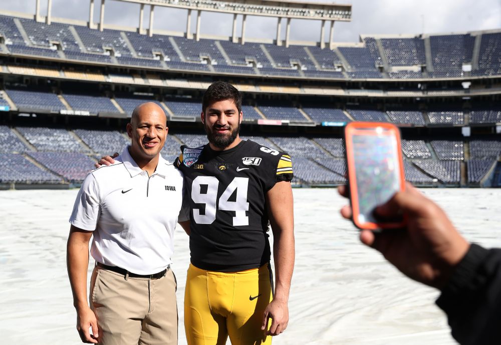 Iowa Hawkeyes special teams coordinator LeVar Woods and defensive end A.J. Epenesa (94) following the team photo Wednesday, December 25, 2019 at SDCCU Stadium in San Diego. (Brian Ray/hawkeyesports.com)