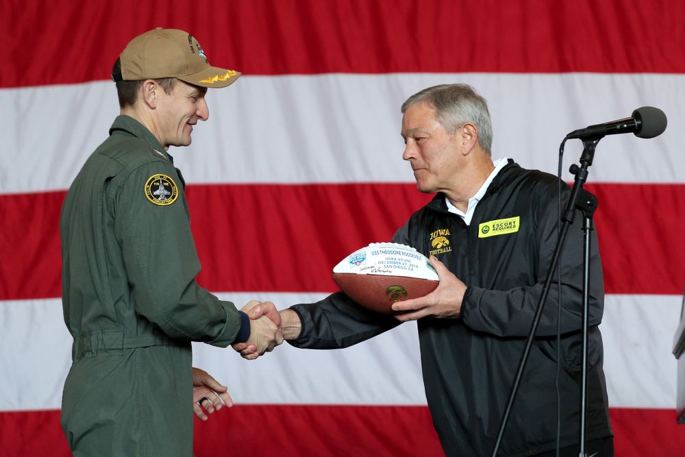 Iowa Hawkeyes head coach Kirk Ferentz presents a ball to Captain Brett Crozier during a tour of the USS Theodore Roosevelt (CVN-71) Tuesday, December 24, 2019 at the Naval Base Coronado. (Brian Ray/hawkeyesports.com)