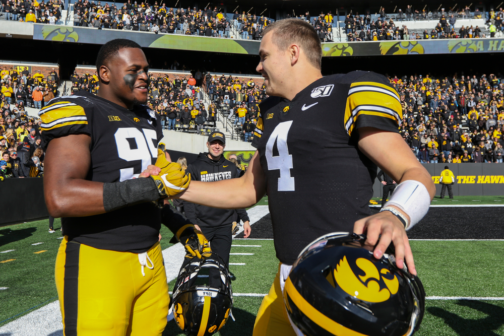 Iowa Hawkeyes quarterback Nate Stanley (4) and Iowa Hawkeyes defensive lineman Cedrick Lattimore (95) during Iowa football vs Illinois on Saturday, November 23, 2019 at Kinnick Stadium. (Lily Smith/hawkeyesports.com)