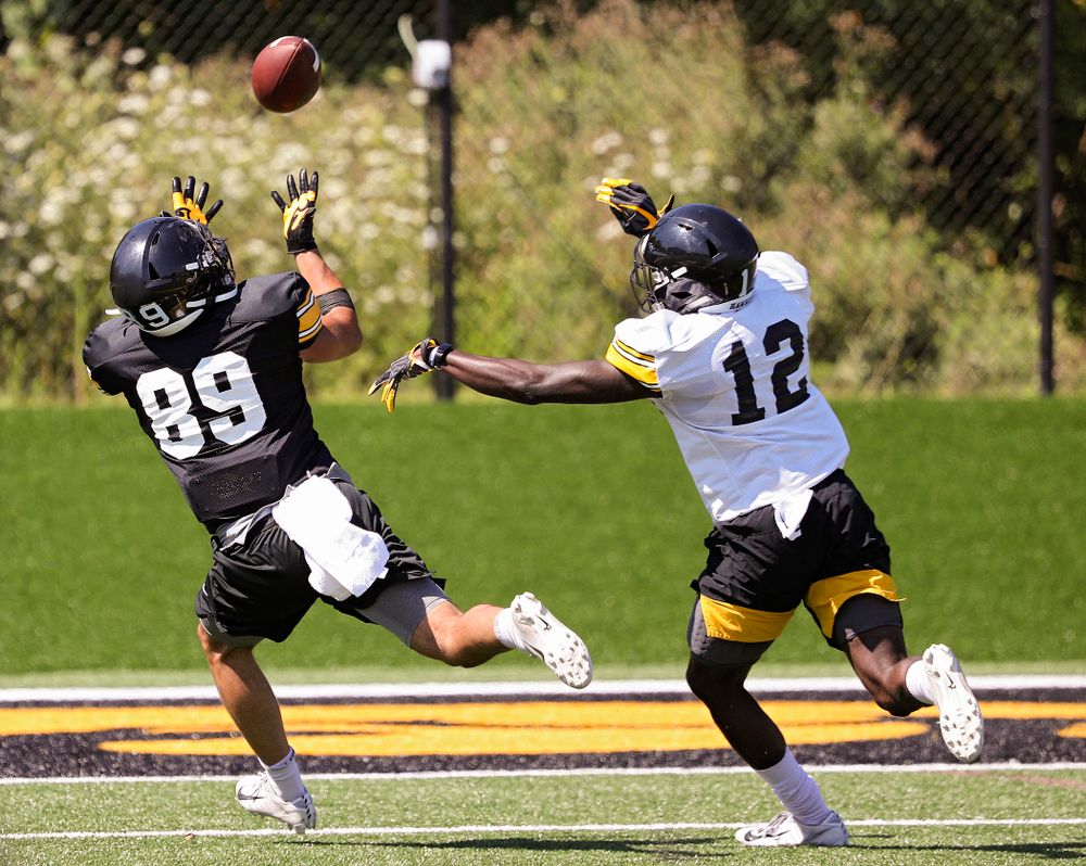 Iowa Hawkeyes wide receiver Nico Ragaini (89) pulls in a pass as defensive back D.J. Johnson (12) gives chase during Fall Camp Practice No. 7 at the Hansen Football Performance Center in Iowa City on Friday, Aug 9, 2019. (Stephen Mally/hawkeyesports.com)
