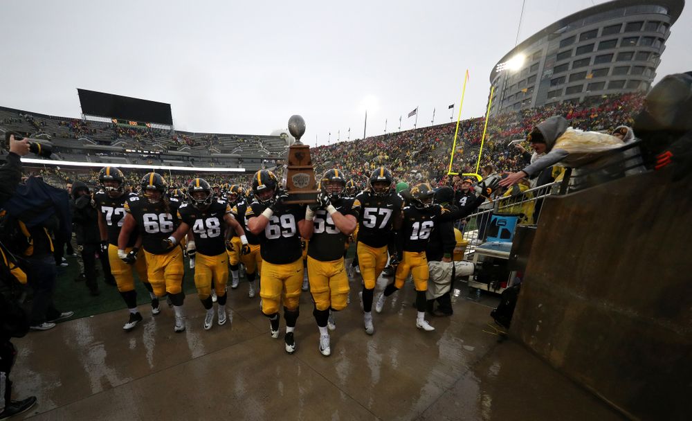 Iowa Hawkeyes offensive lineman Keegan Render (69) and offensive lineman Ross Reynolds (59) carry the Heroes game trophy off the field following their win over the Nebraska Cornhuskers Friday, November 23, 2018 at Kinnick Stadium. (Brian Ray/hawkeyesports.com)