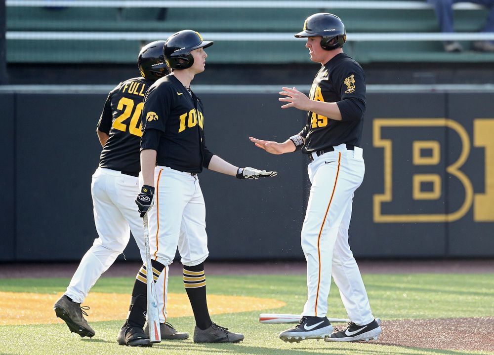 Iowa first baseman Peyton Williams (45) celebrates with infielder Izaya Fullard (20) and designated hitter Trenton Wallace (38) after scoring a run during the third inning of their college baseball game at Duane Banks Field in Iowa City on Tuesday, March 10, 2020. (Stephen Mally/hawkeyesports.com)