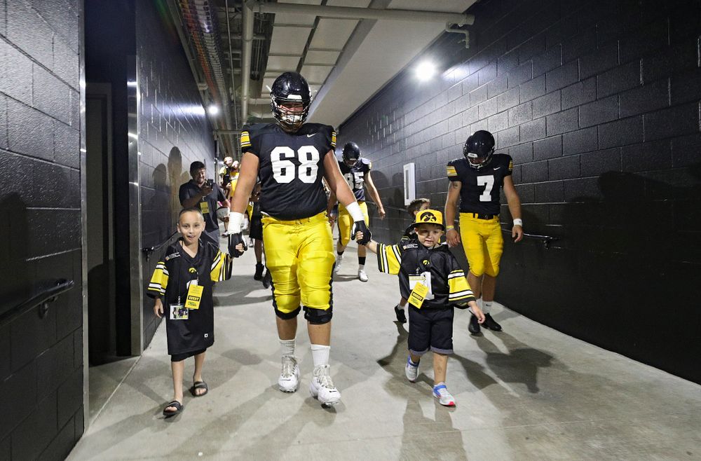 Kid Captains Skylar Hardee (left) and Jeg Weets (right) walk with Iowa Hawkeyes offensive lineman Landan Paulsen (68) down the tunnel during Kids Day at Kinnick Stadium in Iowa City on Saturday, Aug 10, 2019. (Stephen Mally/hawkeyesports.com)