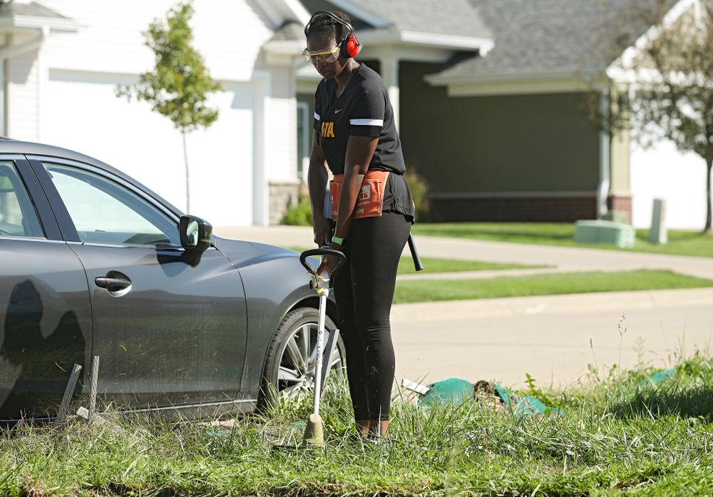 Ugo Nwaigwe, director of basketball operations, cuts down weeds with a trimmer as they work on a Habitat for Humanity Women Build project in Iowa City on Wednesday, Sep 25, 2019. (Stephen Mally/hawkeyesports.com)