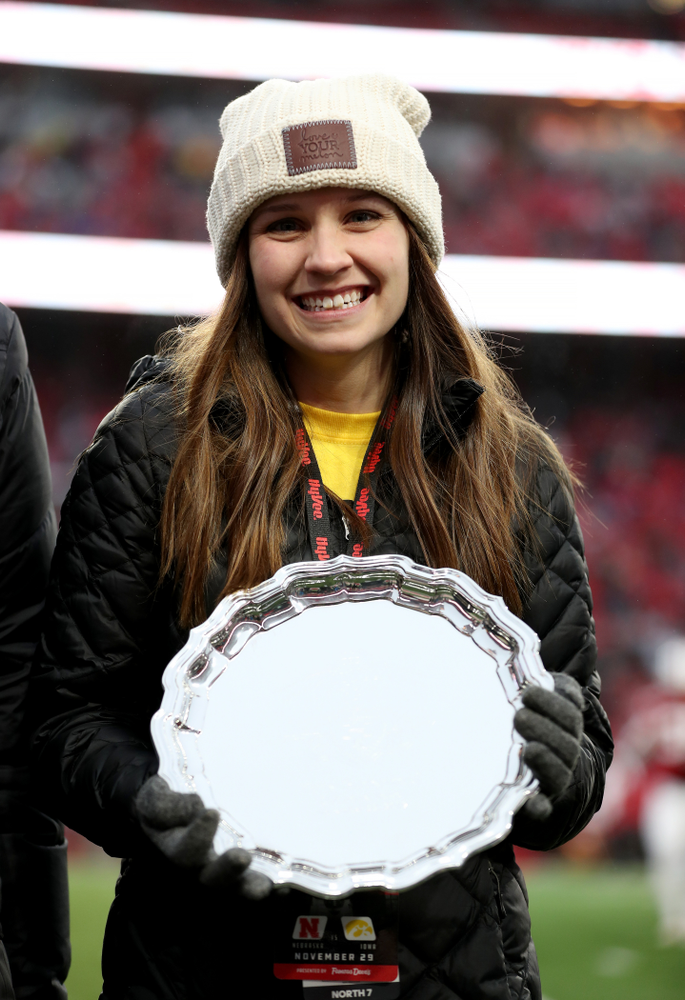 Iowa hero Katie Gudenkauf stands with Iowa Governor Kim Reynolds and Henry B. and Patricia B. Tippie Director of Athletics Chair Gary Barta as she is honored at half-time of the Iowa Hawkeyes game against the Nebraska Cornhuskers Friday, November 29, 2019 at Memorial Stadium in Lincoln, Neb. (Brian Ray/hawkeyesports.com)