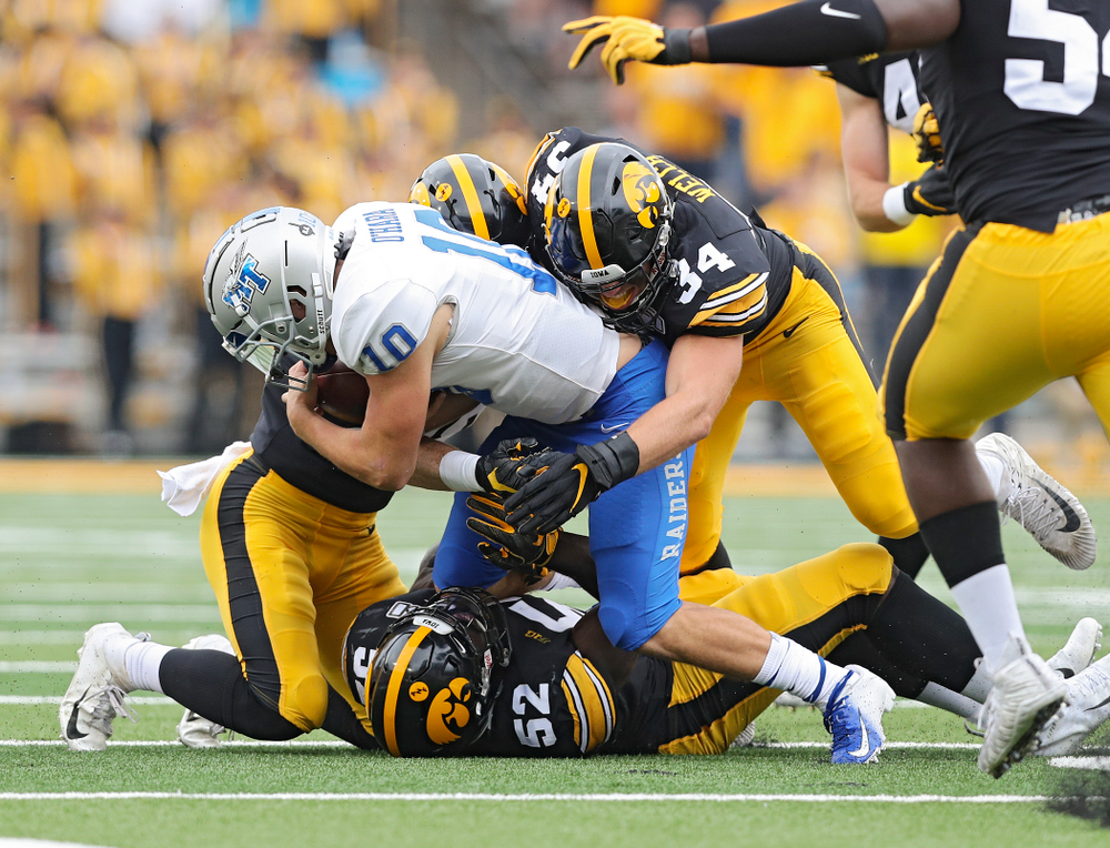 Iowa Hawkeyes defensive back Jack Koerner (28), linebacker Amani Jones (52), and linebacker Kristian Welch (34) make a tackle during third quarter of their game at Kinnick Stadium in Iowa City on Saturday, Sep 28, 2019. (Stephen Mally/hawkeyesports.com)
