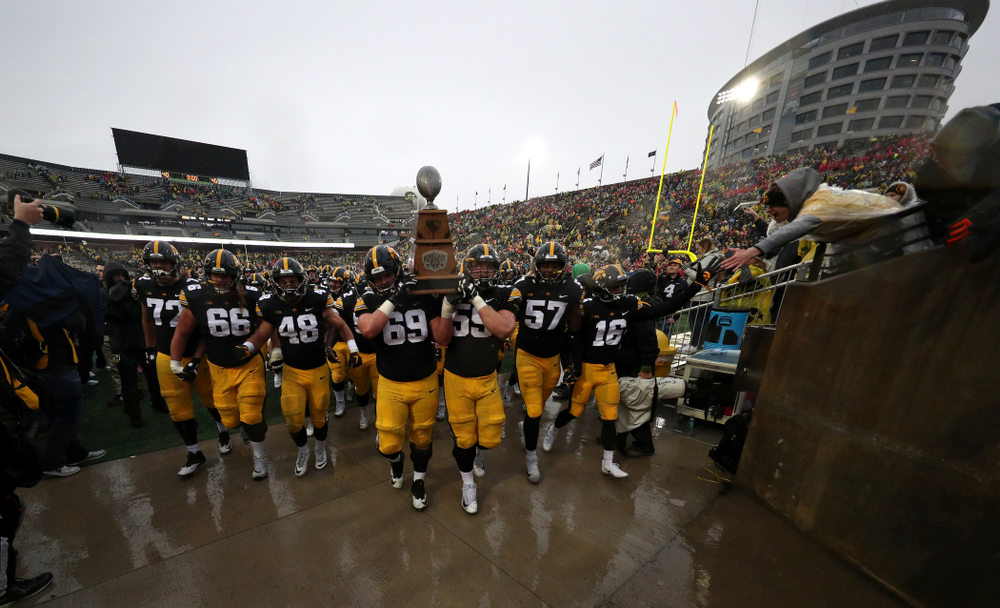 Iowa Hawkeyes offensive lineman Keegan Render (69) and offensive lineman Ross Reynolds (59) carry the Heroes game trophy off the field following their win over the Nebraska Cornhuskers Friday, November 23, 2018 at Kinnick Stadium. (Brian Ray/hawkeyesports.com)