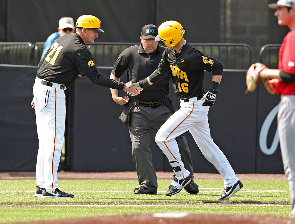 Iowa Hawkeyes head coach Rick Heller shakes hands with shortstop Tanner Wetrich (16) as he rounds the bases after hitting a solo home run during the second inning of their game against Rutgers at Duane Banks Field in Iowa City on Saturday, Apr. 6, 2019. (Stephen Mally/hawkeyesports.com)