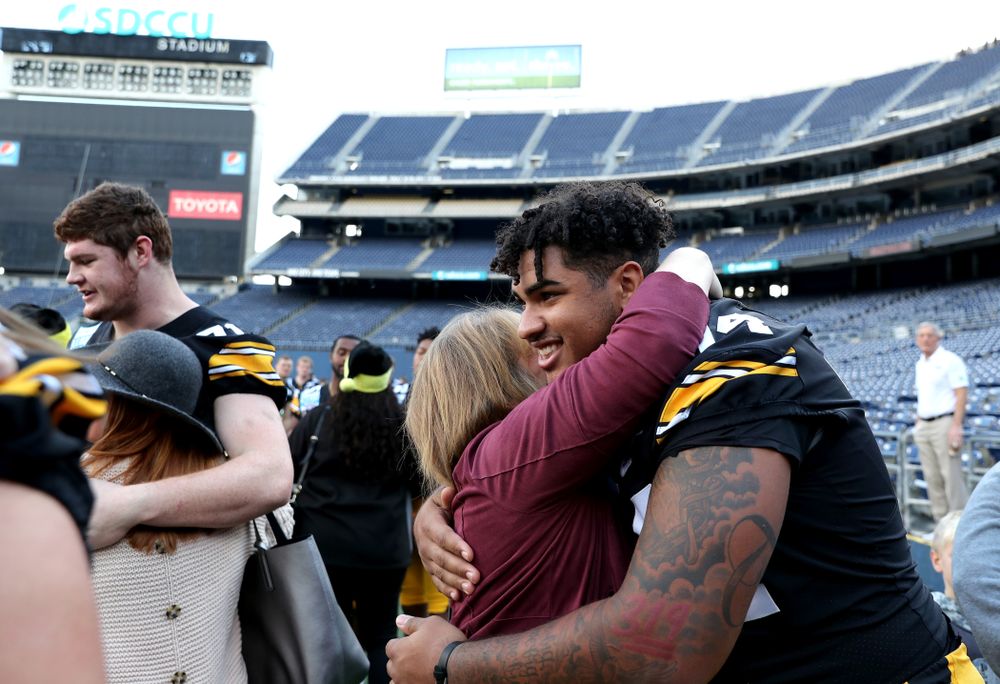Iowa Hawkeyes offensive lineman Tristan Wirfs (74) hugs family members of Kyler Schott following the team photo Wednesday, December 25, 2019 at SDCCU Stadium in San Diego. (Brian Ray/hawkeyesports.com)