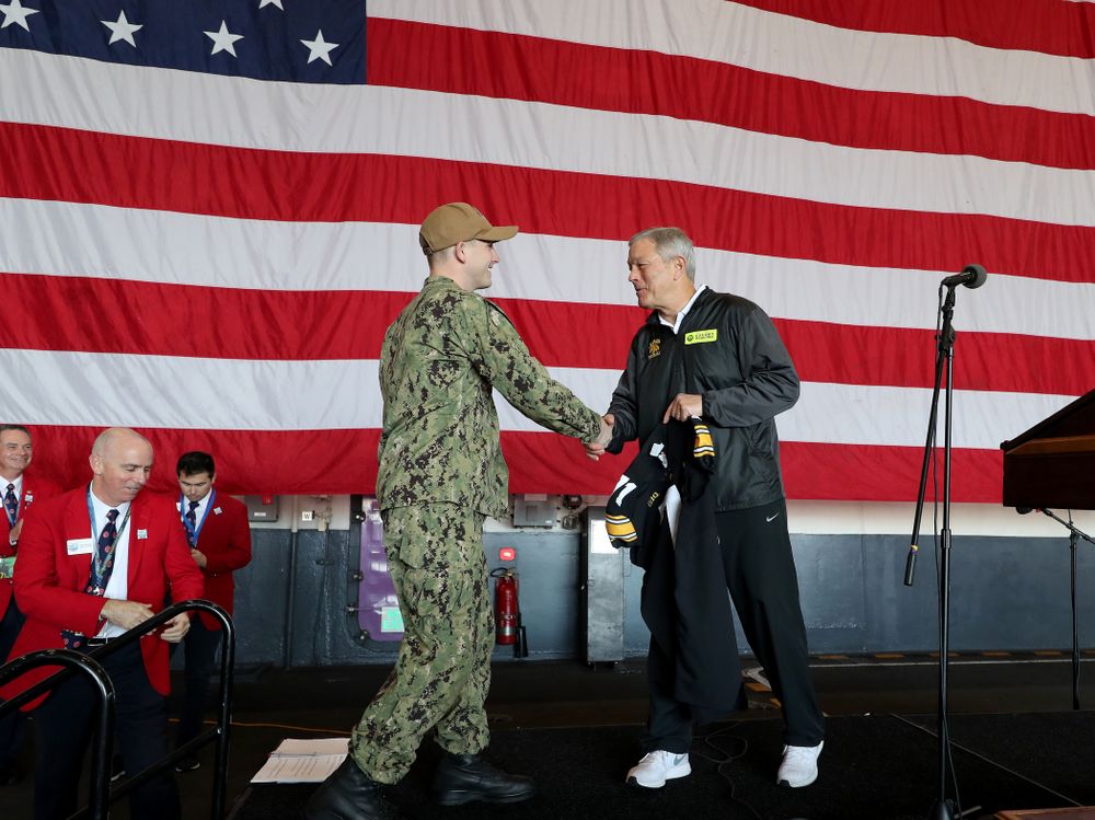 Iowa Hawkeyes head coach Kirk Ferentz presents a jersey to honorary captain Vincent OÕBrien of Bell Plaine during a tour of the USS Theodore Roosevelt (CVN-71) Tuesday, December 24, 2019 at the Naval Base Coronado. (Brian Ray/hawkeyesports.com)