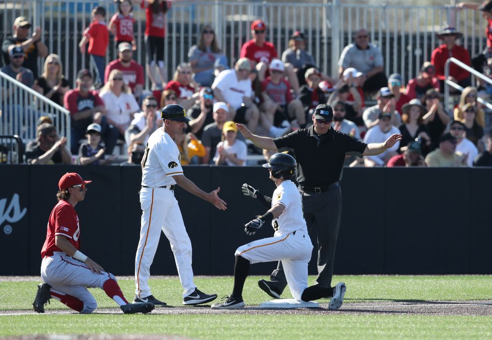 Iowa Hawkeyes infielder Mitchell Boe (4) slaps hands with head coach Rick Heller after tripling against the Nebraska Cornhuskers Saturday, April 20, 2019 at Duane Banks Field. (Brian Ray/hawkeyesports.com)