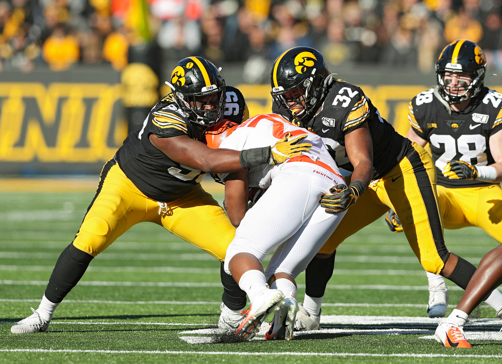 Iowa Hawkeyes defensive lineman Cedrick Lattimore (95) and linebacker Djimon Colbert (32) make a tackle during the third quarter of their game at Kinnick Stadium in Iowa City on Saturday, Nov 23, 2019. (Stephen Mally/hawkeyesports.com)