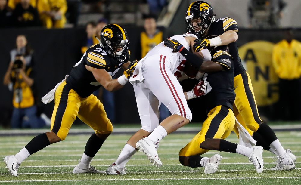Iowa Hawkeyes defensive back Amani Hooker (27), Iowa Hawkeyes defensive back Jake Gervase (30) and Iowa Hawkeyes defensive back Matt Hankins (8) make a tackle during a game against Wisconsin at Kinnick Stadium on September 22, 2018. (Tork Mason/hawkeyesports.com)
