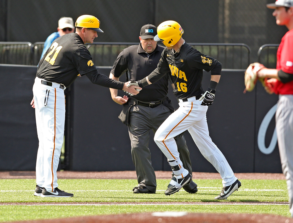Iowa Hawkeyes head coach Rick Heller shakes hands with shortstop Tanner Wetrich (16) as he rounds the bases after hitting a solo home run during the second inning of their game against Rutgers at Duane Banks Field in Iowa City on Saturday, Apr. 6, 2019. (Stephen Mally/hawkeyesports.com)
