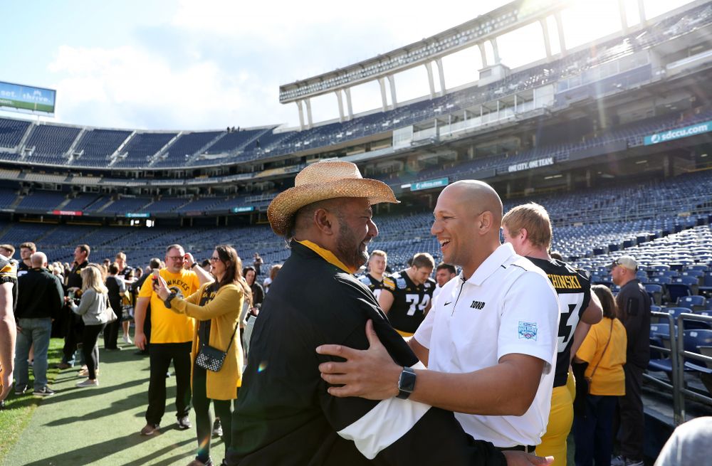 Iowa Hawkeyes special teams coordinator LeVar Woods hugs Eppy Epenesa following the team photo Wednesday, December 25, 2019 at SDCCU Stadium in San Diego. (Brian Ray/hawkeyesports.com)