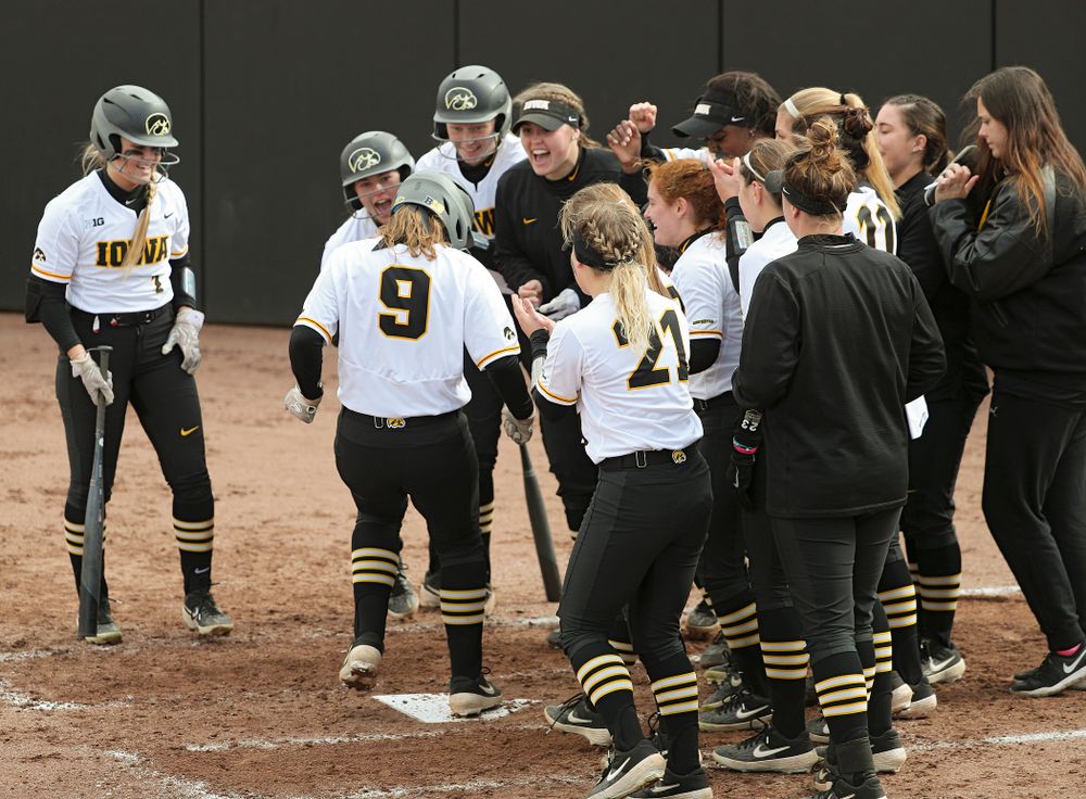 Iowa catcher Abby Lien (9) is greeted at home plate by her teammates after hitting a home run during the second inning of their game against Illinois at Pearl Field in Iowa City on Friday, Apr. 12, 2019. (Stephen Mally/hawkeyesports.com)
