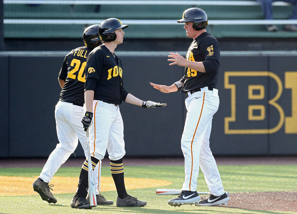 Iowa first baseman Peyton Williams (45) celebrates with infielder Izaya Fullard (20) and designated hitter Trenton Wallace (38) after scoring a run during the third inning of their college baseball game at Duane Banks Field in Iowa City on Tuesday, March 10, 2020. (Stephen Mally/hawkeyesports.com)