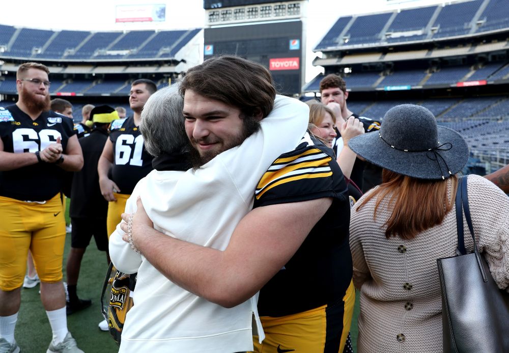 Iowa Hawkeyes offensive lineman Kyler Schott (64) hugs family members following the team photo Wednesday, December 25, 2019 at SDCCU Stadium in San Diego. (Brian Ray/hawkeyesports.com)