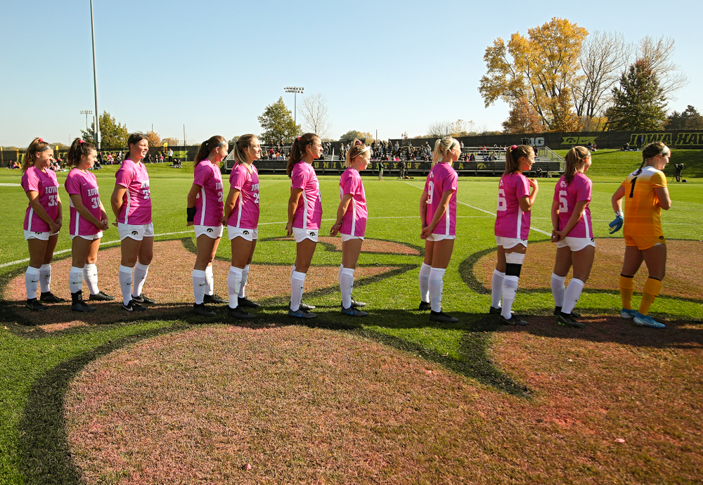 Iowa defender Riley Burns (33), forward Devin Burns (30), forward Samantha Tawharu (27), midfielder Josie Durr (25), defender Sara Wheaton (24), defender Hannah Drkulec (17), midfielder/defender Natalie Winters (10), defender Samantha Cary (9), midfielder Isabella Blackman (6), defender Riley Whitaker (5), and goalkeeper Claire Graves (1) stand for the National Anthem before their match at the Iowa Soccer Complex in Iowa City on Sunday, Oct 27, 2019. (Stephen Mally/hawkeyesports.com)