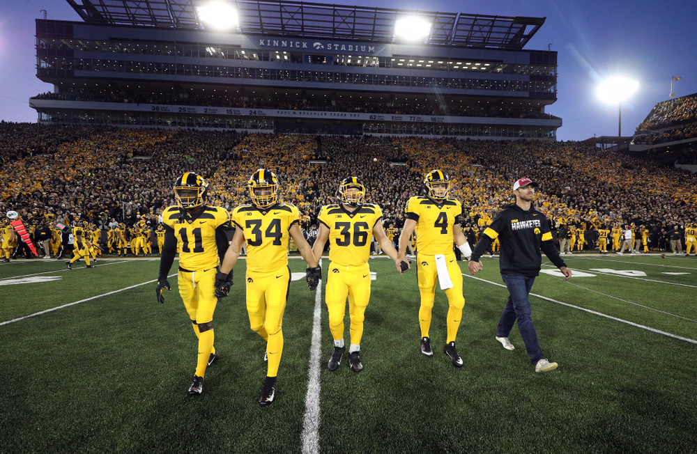 Iowa Hawkeyes captains defensive back Michael Ojemudia (11), linebacker Kristian Welch (34), fullback Brady Ross (36), and quarterback Nate Stanley (4), walk with honorary captain Ricky Stanzi before their game against the Penn State Nittany Lions Saturday, October 12, 2019 at Kinnick Stadium. (Brian Ray/hawkeyesports.com)