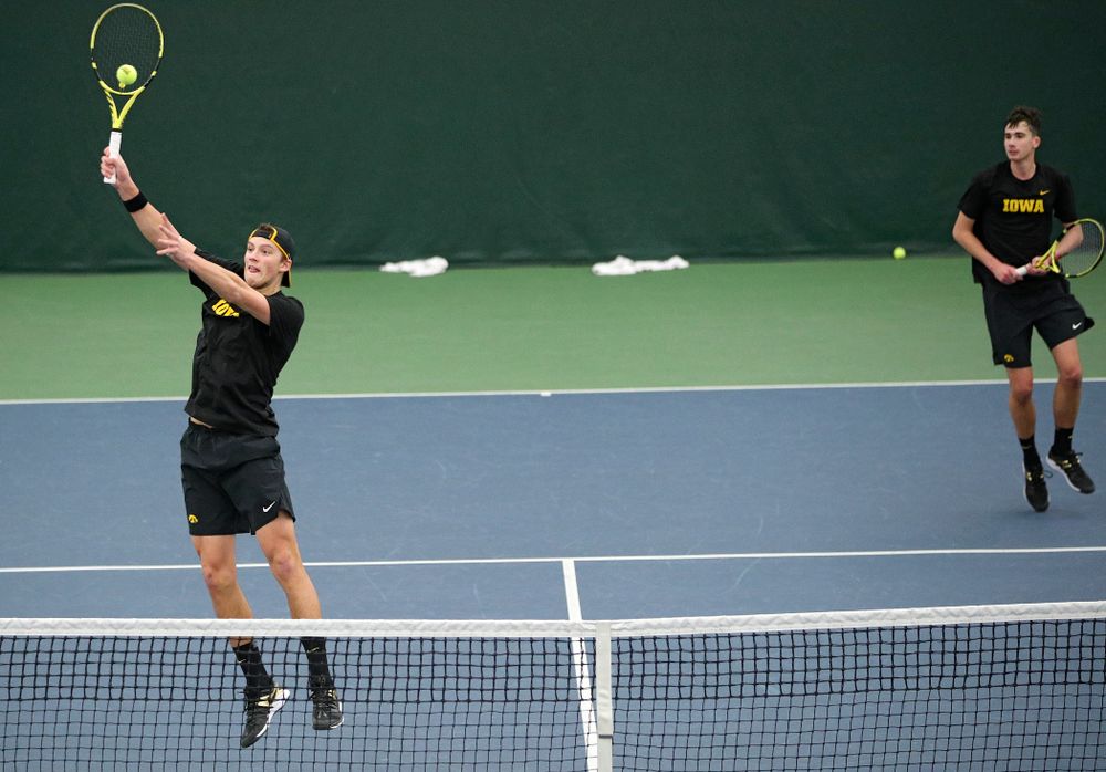 Iowa’s Joe Tyler (from left) hits a shot as Matt Clegg looks on during their doubles match against Marquette at the Hawkeye Tennis and Recreation Complex in Iowa City on Saturday, January 25, 2020. (Stephen Mally/hawkeyesports.com)