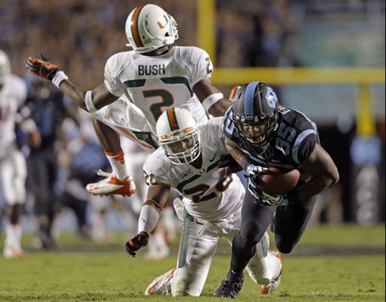 North Carolina's Eric Ebron (85) gains some yardage following a pass reception as Miami's Deon Bush (2) and Rayshawn Jenkins defend during the first...