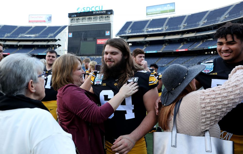 Iowa Hawkeyes offensive lineman Kyler Schott (64) hugs family members following the team photo Wednesday, December 25, 2019 at SDCCU Stadium in San Diego. (Brian Ray/hawkeyesports.com)
