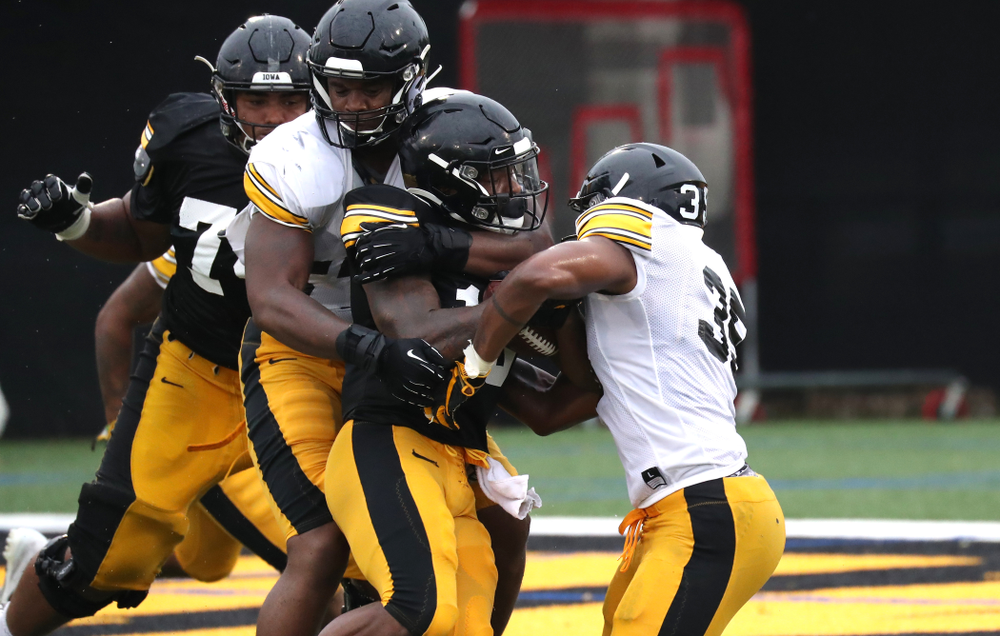 Iowa Hawkeyes defensive end Chauncey Golston (57) and Linebacker Barrington Wade (35) tackle running back Mekhi Sargent (10)