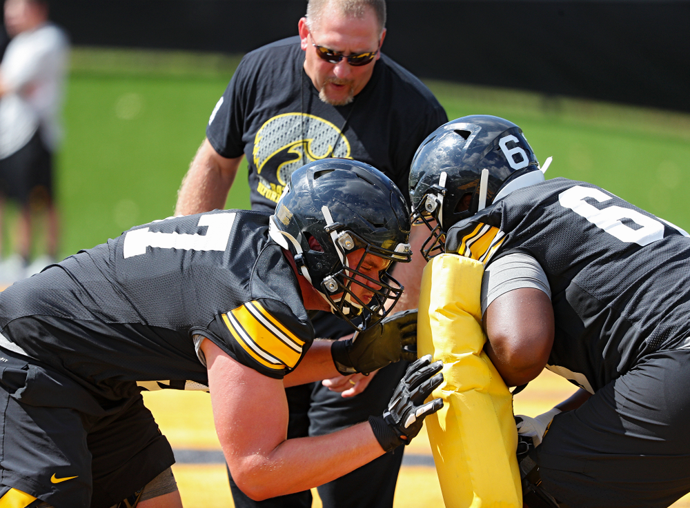 Iowa Hawkeyes offensive lineman Clayton Thurm (57) and offensive lineman Justin Britt (63) run a drill as offensive line coach Tim Polasek looks on during Fall Camp Practice No. 13 at the Hansen Football Performance Center in Iowa City on Friday, Aug 16, 2019. (Stephen Mally/hawkeyesports.com)