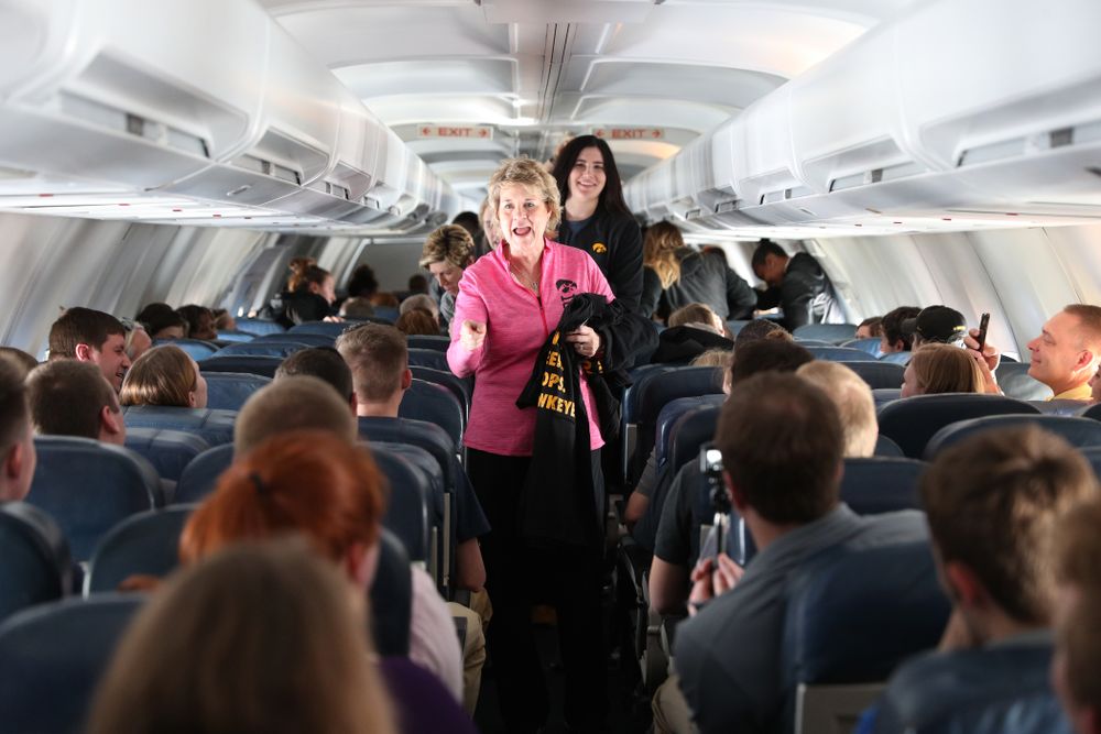 Iowa Hawkeyes head coach Lisa Bluder hands out t-shirts to the band and spirit squad on board the team plane to Greensboro, NC for the Regionals of the 2019 NCAA Women's Basketball Championships Thursday, March 28, 2019 at the Eastern Iowa Airport. (Brian Ray/hawkeyesports.com)