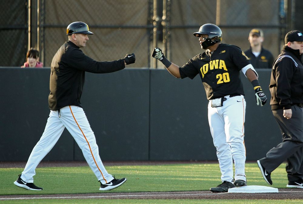 Iowa Hawkeyes head coach Rick Heller (from left) gives infielder Izaya Fullard (20) a first bump after he hit a triple during the third inning of their game at Duane Banks Field in Iowa City on Tuesday, March 3, 2020. (Stephen Mally/hawkeyesports.com)
