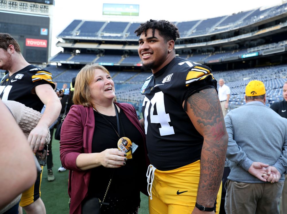 Iowa Hawkeyes offensive lineman Tristan Wirfs (74) hugs family members of Kyler Schott following the team photo Wednesday, December 25, 2019 at SDCCU Stadium in San Diego. (Brian Ray/hawkeyesports.com)