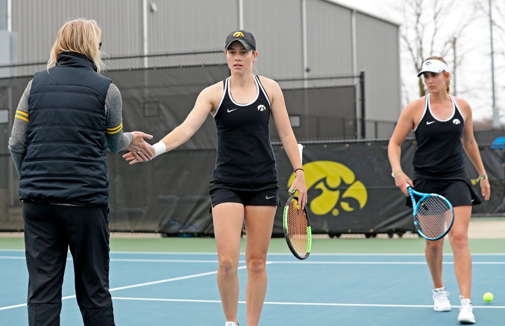Iowa's head coach Sasha Schmid (from left) greets Elise van Heuvelen Treadwell and Ashleigh Jacobs during their doubles match against Rutgers at the Hawkeye Tennis and Recreation Complex in Iowa City on Friday, Apr. 5, 2019. (Stephen Mally/hawkeyesports.com)