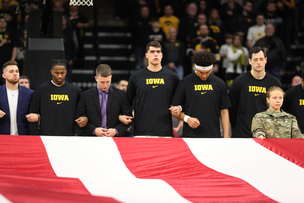 Iowa Hawkeyes guard Jordan Bohannon (3), guard Bakari Evelyn (4), guard Aidan Vanderloo (51 ), forward Luka Garza (55), forward Cordell Pemsl (35), and forward Ryan Kriener (15) as Members of the Iowa Army ROTC display a large American flag before their game against Penn State Saturday, February 29, 2020 at Carver-Hawkeye Arena. (Brian Ray/hawkeyesports.com)