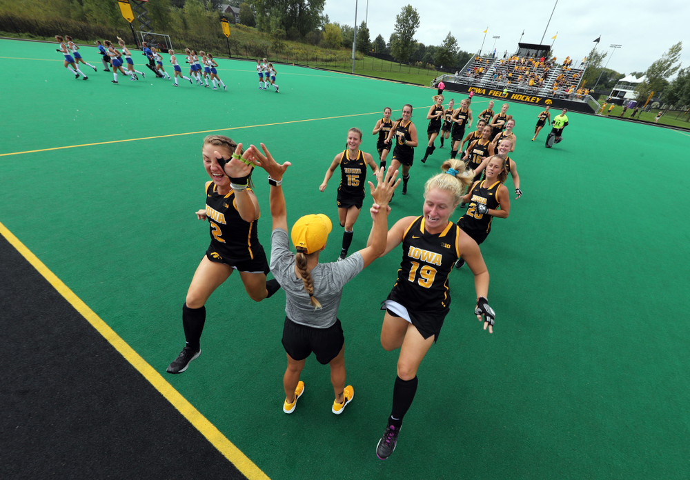 Iowa Hawkeyes defenseman Emily Deuell (2) and forward Ryley Miller (19) slap hands with assistant coach Roz Ellis before their game against the Duke Blue Devils Sunday, September 15, 2019 at Grant Field. (Brian Ray/hawkeyesports.com)