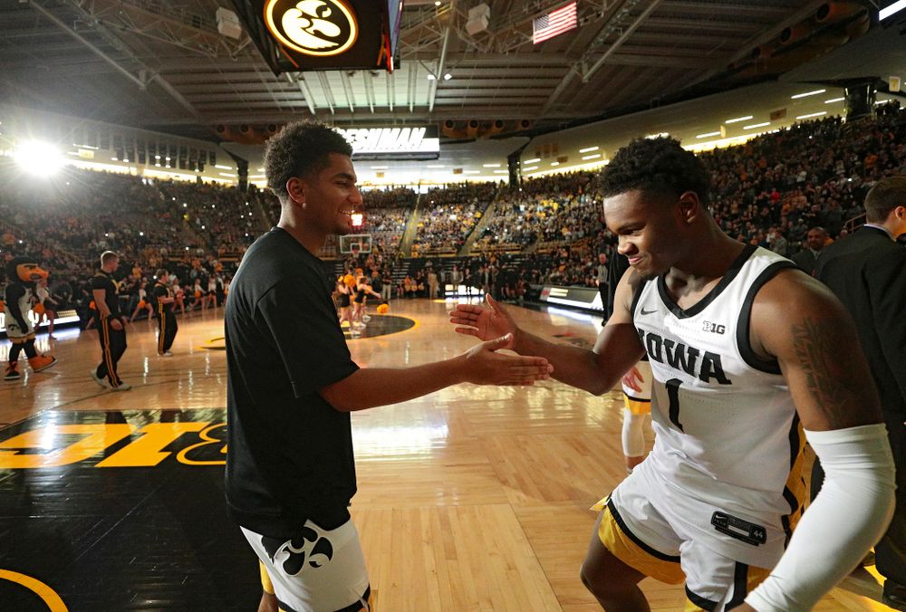 Iowa Hawkeyes guard Nicolas Hobbs (24) greets guard Joe Toussaint (1) as he is introduced before the game at Carver-Hawkeye Arena in Iowa City on Sunday, December 29, 2019. (Stephen Mally/hawkeyesports.com)