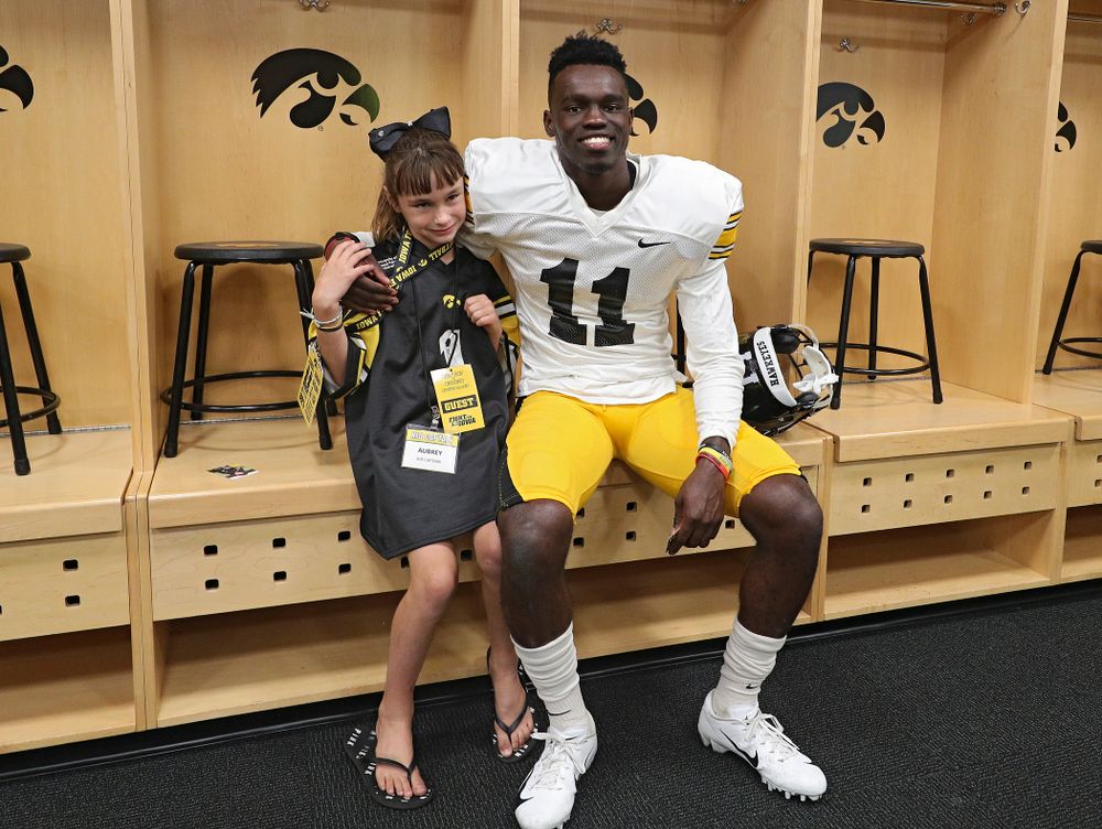 Kid Captain Aubrey Bussan-Kluesner takes a picture with defensive back Michael Ojemudia (11) during Kids Day at Kinnick Stadium in Iowa City on Saturday, Aug 10, 2019. (Stephen Mally/hawkeyesports.com)