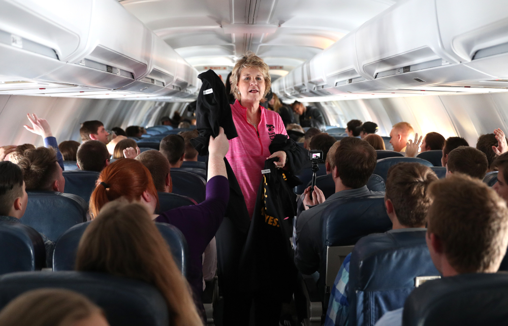 Iowa Hawkeyes head coach Lisa Bluder hands out t-shirts to the band and spirit squad on board the team plane to Greensboro, NC for the Regionals of the 2019 NCAA Women's Basketball Championships Thursday, March 28, 2019 at the Eastern Iowa Airport. (Brian Ray/hawkeyesports.com)