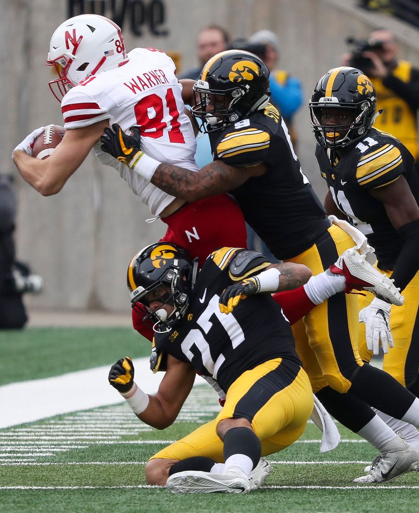 Iowa Hawkeyes defensive back Amani Hooker (27), Iowa Hawkeyes defensive back Geno Stone (9) and Iowa Hawkeyes defensive back Michael Ojemudia (11) make a tackle during a game against Nebraska at Kinnick Stadium on November 23, 2018. (Tork Mason/hawkeyesports.com)