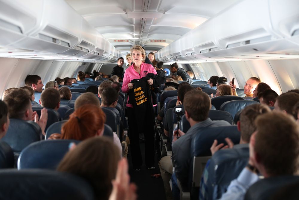 Iowa Hawkeyes head coach Lisa Bluder hands out t-shirts to the band and spirit squad on board the team plane to Greensboro, NC for the Regionals of the 2019 NCAA Women's Basketball Championships Thursday, March 28, 2019 at the Eastern Iowa Airport. (Brian Ray/hawkeyesports.com)